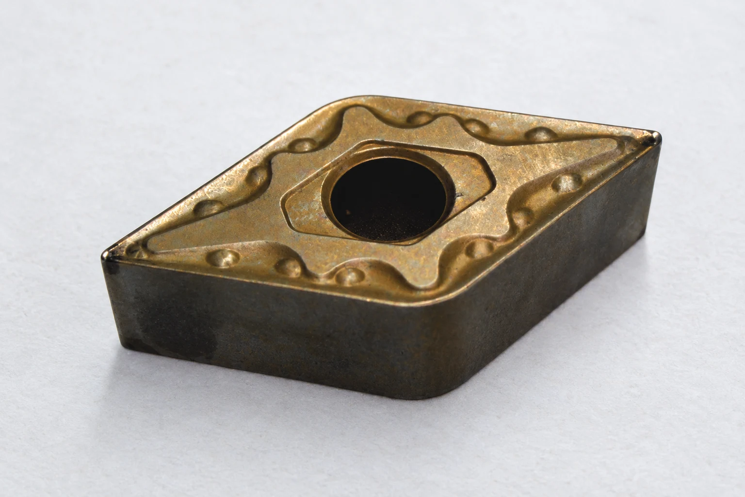 Macro view of a diamond-shaped turning insert edge; photo-based editorial edit