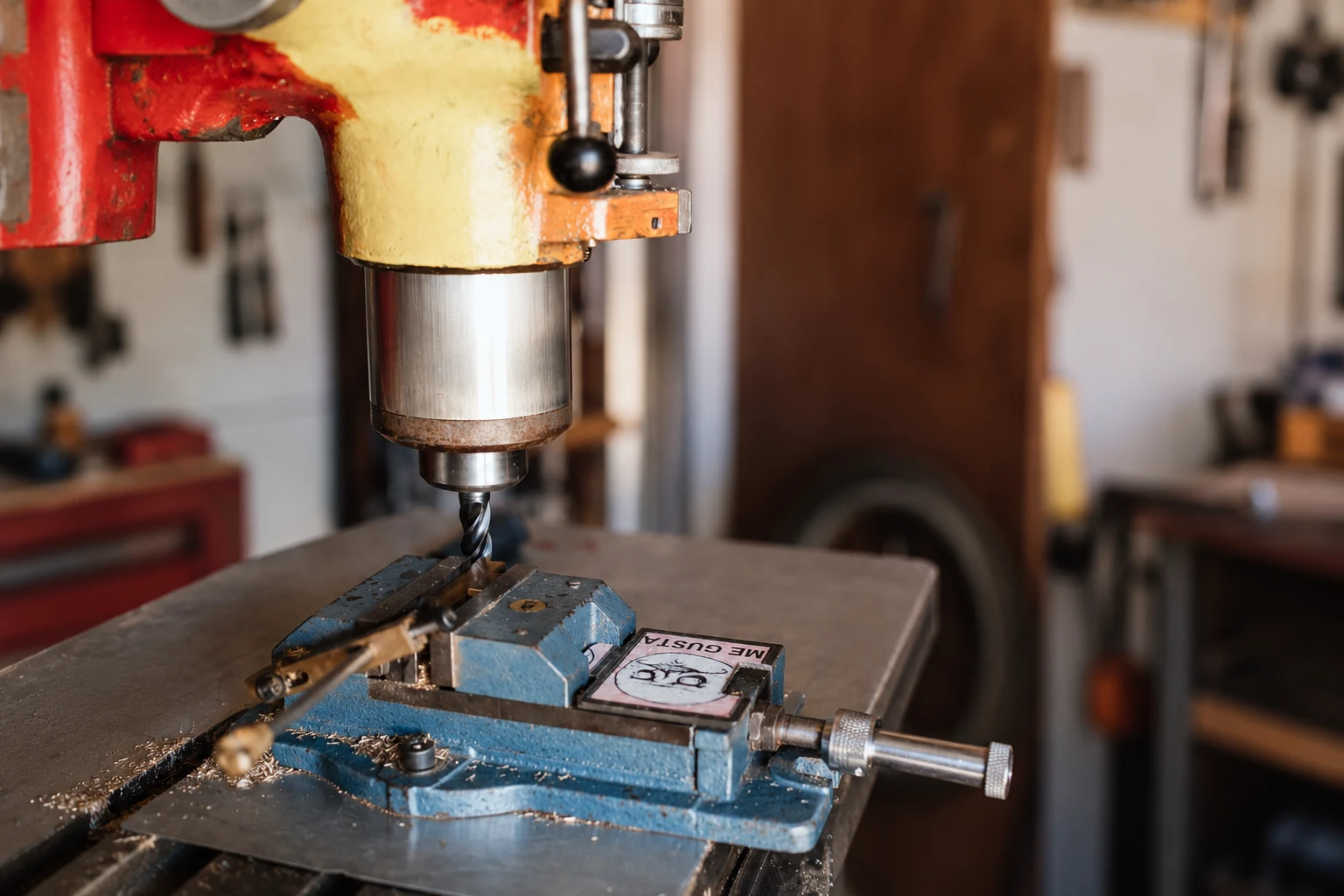 Drill press spindle and workpiece clamped in a blue vise; photo-based editorial edit