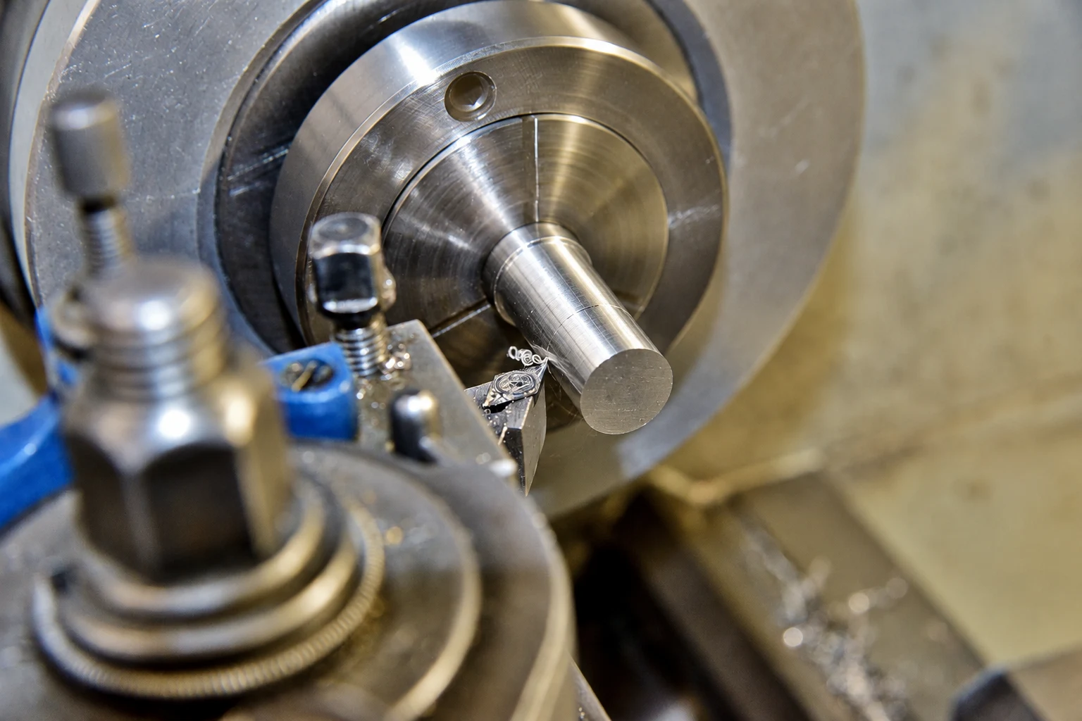 Photo-based editorial illustration of a carbide turning tool at a silver-colored cylindrical workpiece