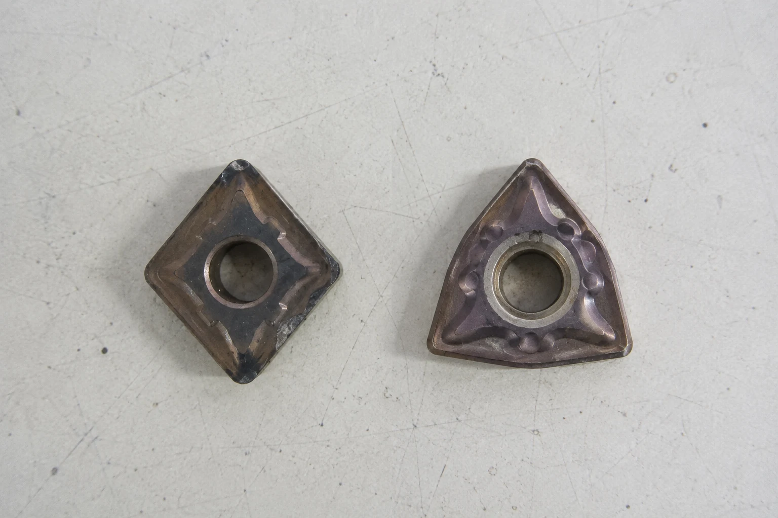 Photo-based editorial comparison of rhombic and trigon turning insert shapes