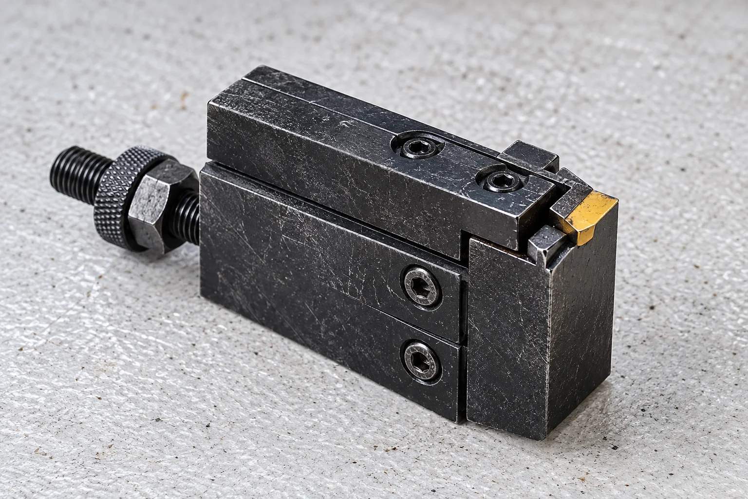Worn black parting and grooving tool assembly with a yellow cutting tip, editorially rendered